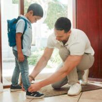 photo of father and son adjusting shoes at home getting ready for school